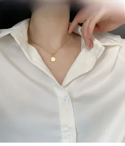 Dettaglio di una collana dorata con incisione Good Luck indossata da una modella