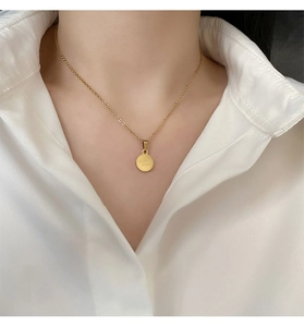 Dettaglio della collana in titanio dorato con ciondolo inciso 'Good Luck' sul collo