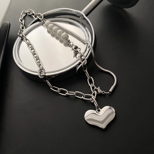 Hip hop titanium steel necklace with white pearls and heart pendant on mirrored surface