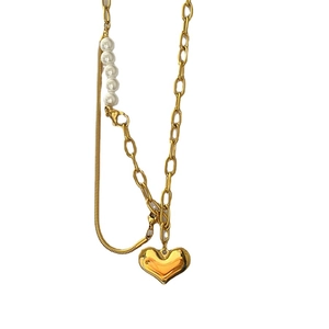 Asymmetric gold necklace with heart pendant featuring bold links and elegant pearls