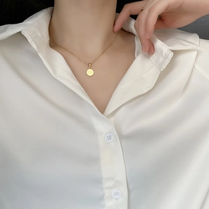 Collana minimalista in acciaio al titanio dorato con ciondolo tondo Good Luck su modella