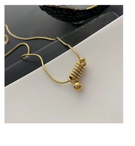 Gros plan d'un pendentif spirale doré sur une fine chaîne serpent en acier inoxydable