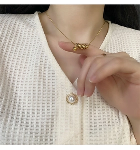Détail du pendentif spirale dorée sur une chaîne serpent portée par un mannequin