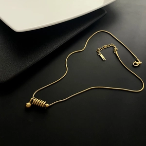 Collier chaîne serpent en acier titane doré avec pendentif spirale sur fond noir