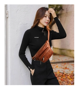 Close-up of brown soft PU leather waist bag with zipper pockets worn by a model