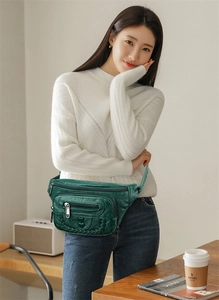 Detail of dark green multi-pocket waist bag with litchi texture and heart buckle