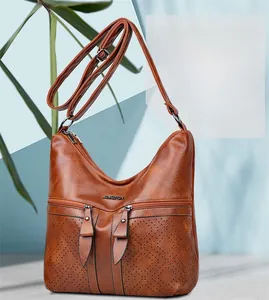 Détail d'un sac à main en cuir marron souple avec fermetures éclair et ornements métalliques