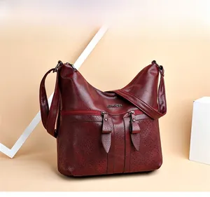 Détail du sac à bandoulière vintage bordeaux avec motifs ajourés au laser et double zip