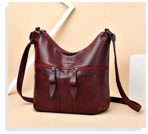 Détail du sac à bandoulière en cuir PU bordeaux avec texture litchi et motifs laser