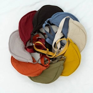 Collection of lightweight nylon crescent crossbody bags in eight vibrant colors on white fabric