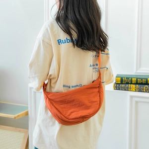 Lightweight burnt orange nylon crescent crossbody bag styled for daily casual wear