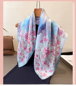 Detail of light blue silk scarf with pink carnation prints hanging on wooden hanger