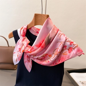 Detail view of pink floral faux silk square scarf tied on a black top with accessories