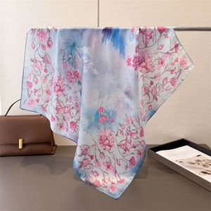 Macro detail of elegant light blue silk scarf with fine pink floral patterns and soft drape