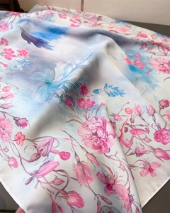 Macro detail of floral print silk scarf showing smooth satin texture and pink roses