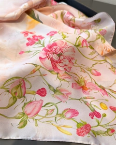 Macro detail of pink floral print silk scarf with fine stitching and satin texture