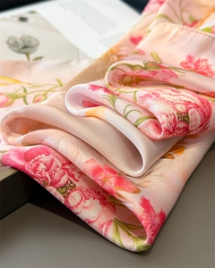 Detailed close-up of pink floral faux silk scarf showing smooth satin texture and drape
