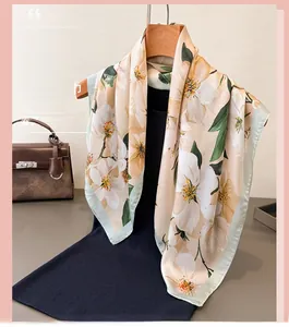 Détail d'un foulard en soie aux élégantes fleurs jaunes et bordures vertes stylées