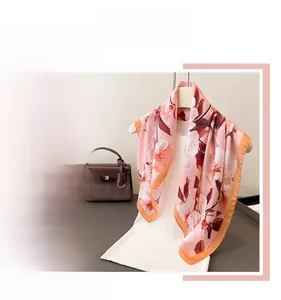 Détail d'un foulard en soie à imprimé floral de cerisier avec bordure orange vif