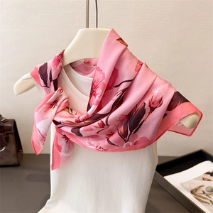 Vue détaillée d'un foulard en soie rose à fleurs avec un haut blanc et accessoires