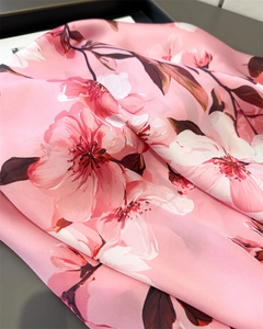 Détail d'un foulard en soie rose avec imprimé cerisier et texture satinée lisse