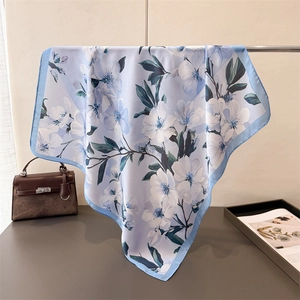 Détail d'un foulard floral bleu clair suspendu délicatement sur un support en métal