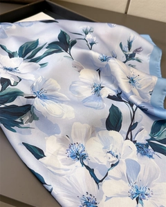 Gros plan d'un foulard en soie bleu clair avec motifs floraux et bords cousus