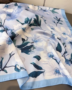 Détail d'un foulard en soie bleu clair avec imprimé floral et texture satinée premium