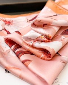 Détail d'un foulard en soie à fleurs montrant la texture lisse et les bords roulés