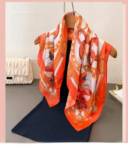 Detail of silk-like scarf with orange chain and equestrian pattern on a wooden hanger