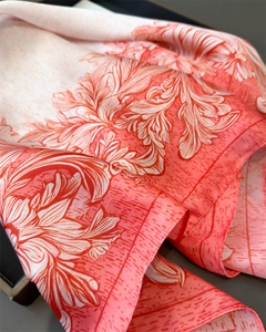 Close-up of silk-like scarf with coral floral print and fine rolled edge texture