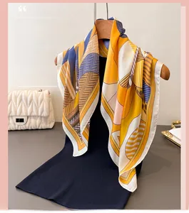 Detail of silk-like square scarf featuring geometric patterns on a wooden hanger