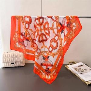 Detailed view of silk square scarf with golden chain patterns and floral prints
