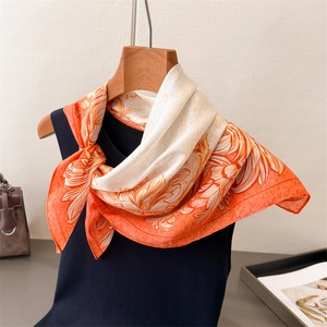 Close-up of orange floral silk scarf draped elegantly on a hanger for styling