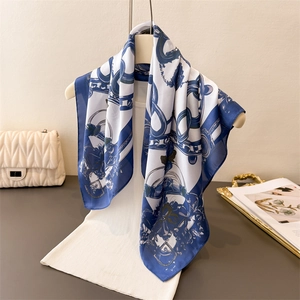 Blue and white silk scarf with luxury chain print draped on white knitwear