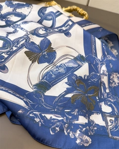 Close-up of blue and white silk scarf with luxury chain and orchid patterns
