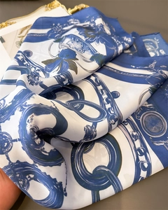 Detailed view of luxury silk scarf showing blue chain patterns and smooth texture