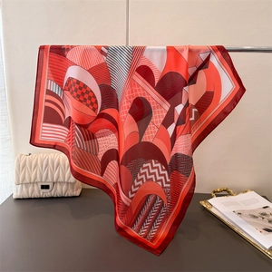 Detailed view of geometric print silk scarf with vibrant orange and red abstract patterns