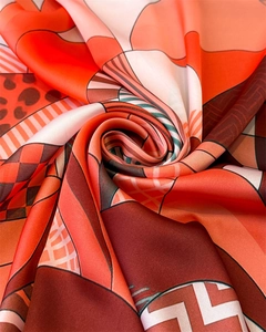 Detailed macro view of silky geometric print square scarf with vibrant orange tones