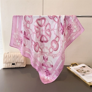 Close-up of pink chain print silk scarf draped over a gold stand with elegant texture