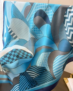 Detailed close-up showing the smooth texture and geometric silk scarf fabric draping naturally