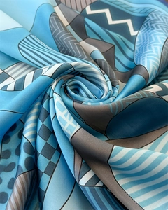 Macro shot of geometric print silk scarf showing soft texture and spiral pleats