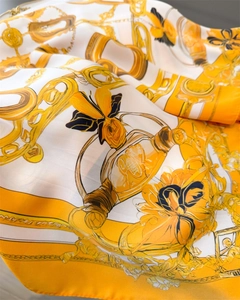 Detailed close-up of chain print silk scarf with golden butterflies and perfume bottles
