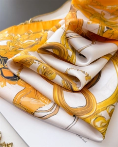 Macro detail of silk scarf featuring gold chain and luxury horse bridle prints