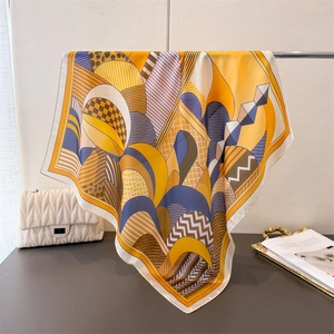 Close-up of geometric silk-like scarf with blue and yellow patterns on a metal rack