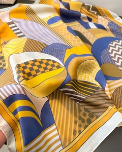 Detail of satin silk scarf featuring yellow checkerboard and geometric wave patterns