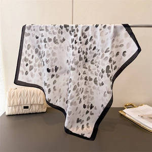 Detail eines seidigen Tuches mit handgezeichneten grauen Herzmustern und schwarzem Rand