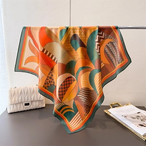 Detail of silk-like satin square scarf with geometric patterns and green hem edge