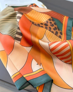 Detailed view of luxury silk scarf showing geometric leopard print and fine rolled edges