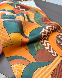 Macro detail of geometric silk scarf showing glossy texture and abstract prints